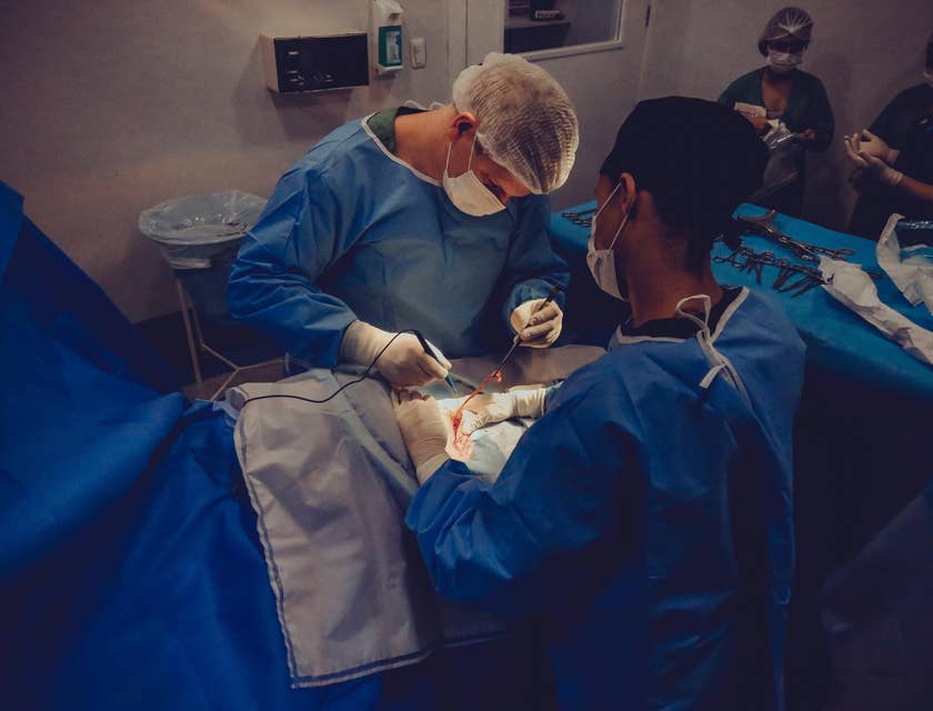 Surgical Assistant holds the patient's body while the surgeon was applying sutures during the operation