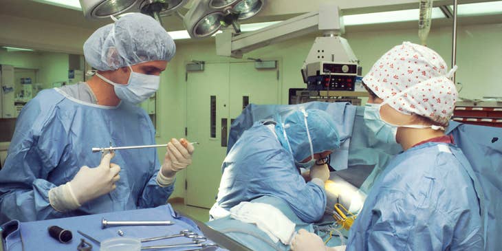 Surgical technologist carefully holds surgical equipment during an operation