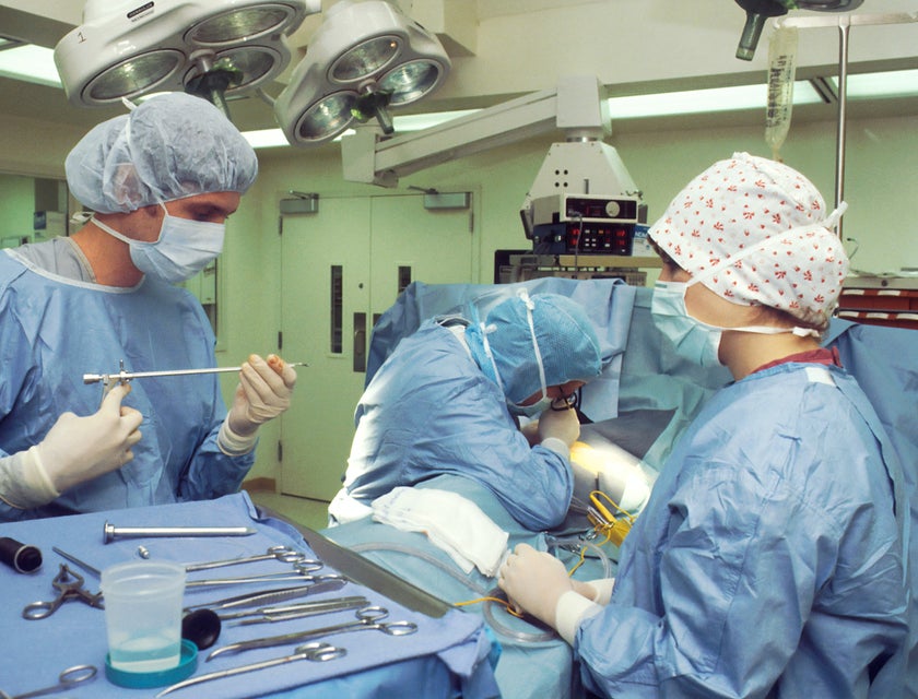 Surgical technologist carefully holds surgical equipment during an operation