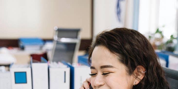 Tax Accountant prepares a tax return report on a laptop while talking to someone on a mobile phone