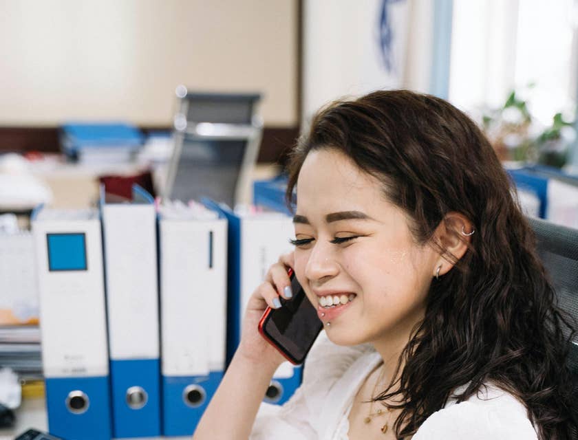 Tax Accountant prepares a tax return report on a laptop while talking to someone on a mobile phone