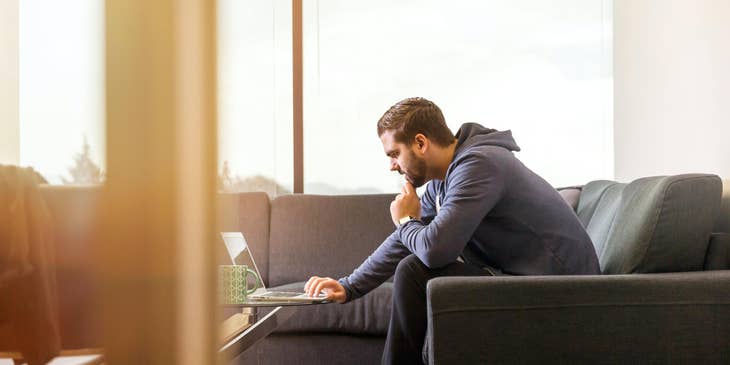 web developer working on his laptop in a building with large windows
