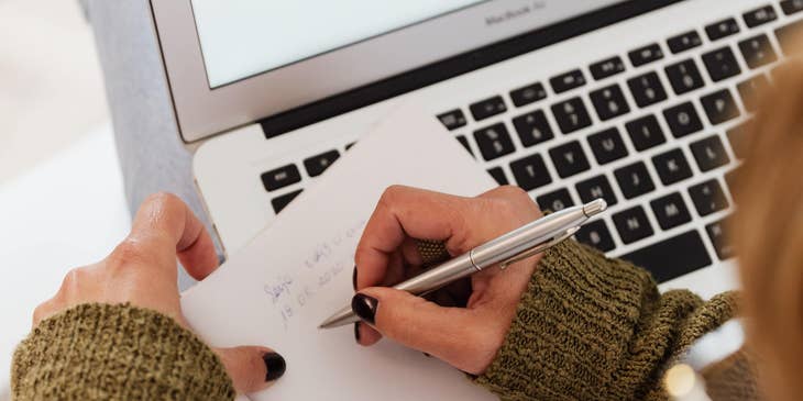 Wedding planner taking down notes while working on her laptop