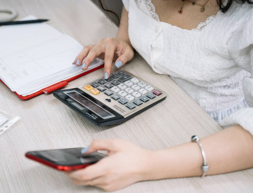 Accounting Intern holding a smartphone while using the calculator