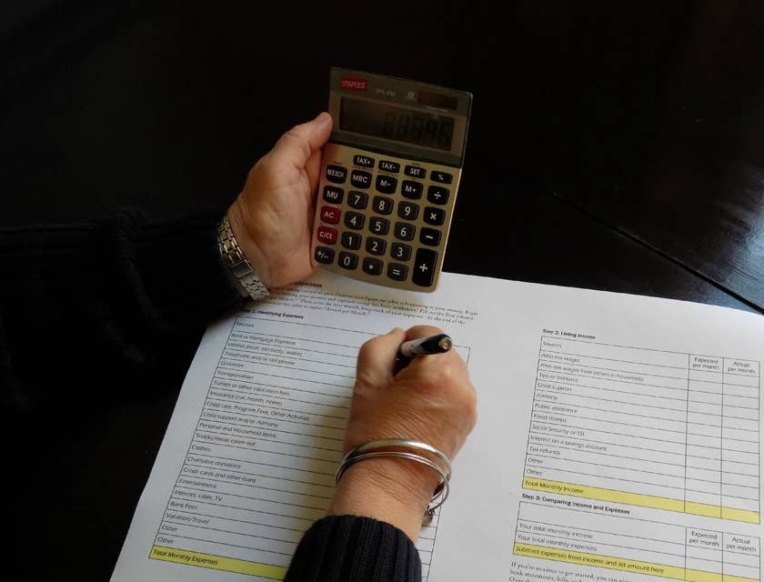 Accounting Officer writing down on a paper while holding a calculator