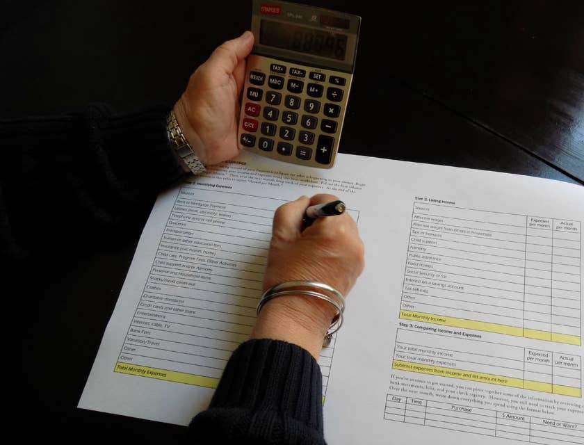 Accounting Officer writing down on a paper while holding a calculator