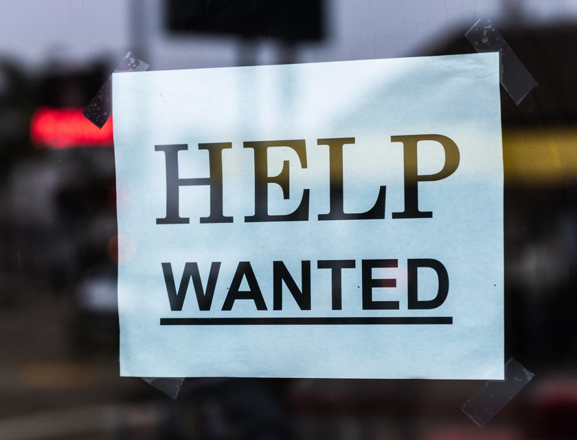 A "help wanted" sign behind glass.