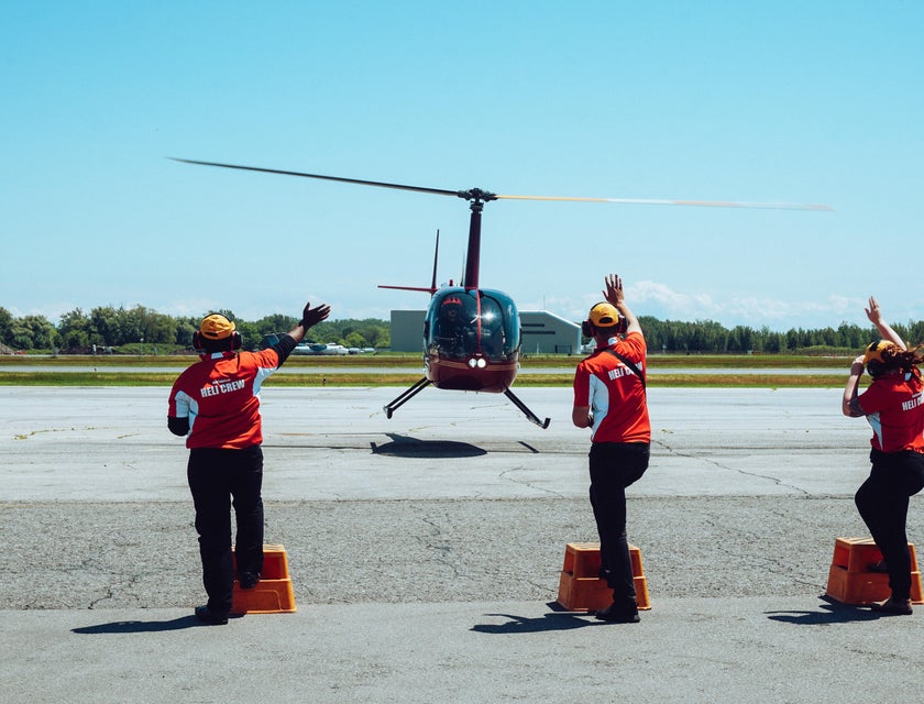 A Group of Air Traffic Controllers assisting a pilot in a helicopter upon arrival.
