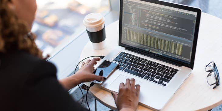 AngularJS Developer working on her laptop with her phone and coffee cup on the desk