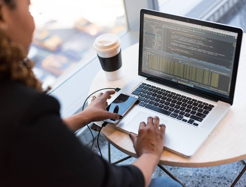 AngularJS Developer working on her laptop with her phone and coffee cup on the desk