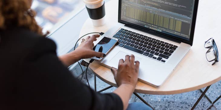 AngularJS Developer working on her laptop with her phone and coffee cup on the desk