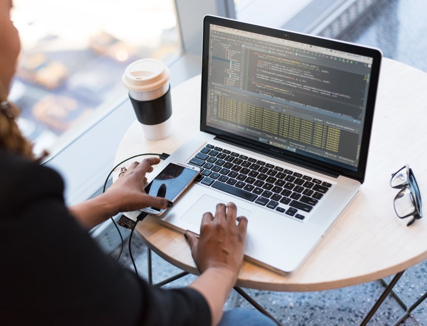 AngularJS Developer working on her laptop with her phone and coffee cup on the desk