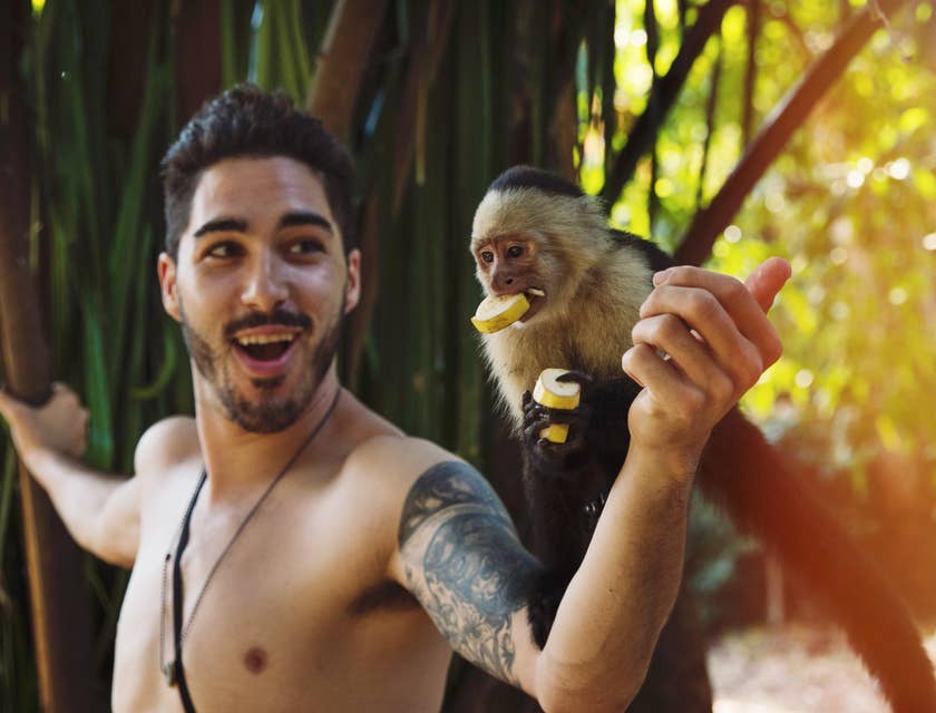 Anthropologist feeding a capuchin on his expedition to study the native animals of a certain island