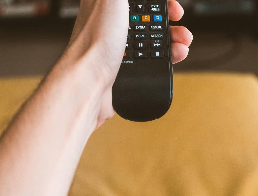 Appliance Repair Technician checking if a tv is working using a remote