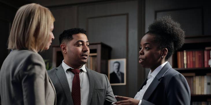 An Arbitrator in the middle of two female clients facilitating communication to settle disputes.