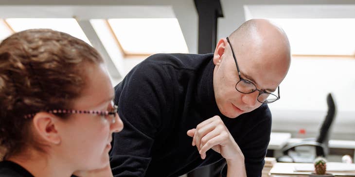Architectural Drafter checks the drawing done by his teammate for a client presentation