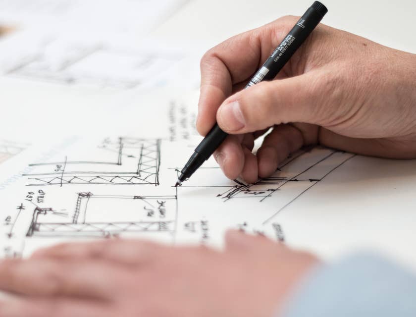 Architectural Engineer holding a black pen and revising the floor plan of a building