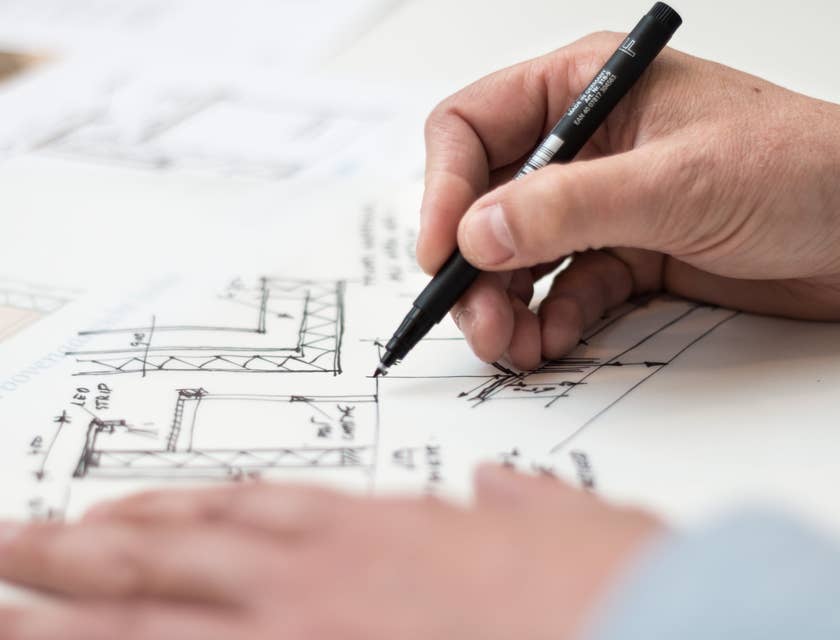 Architectural Engineer holding a black pen and revising the floor plan of a building