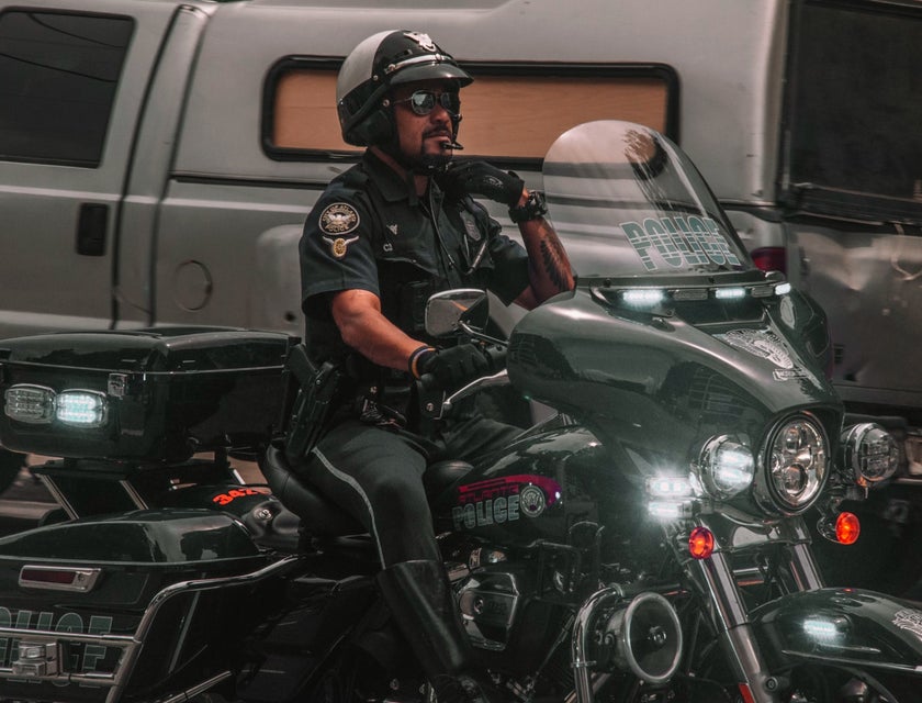Armed Security Officer reaching for his lapel and riding a motorcycle on his way to report for work