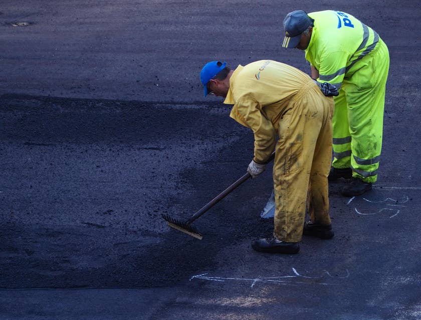 Asphalt Laborers smoothing and setting asphalt on the road.