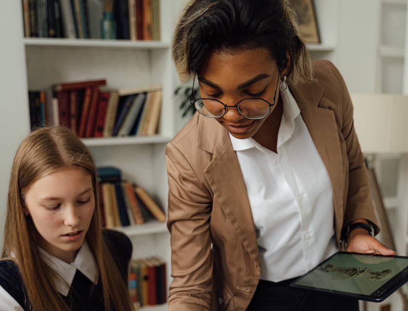 Assessor checking her student's answer on a notepad while looking at a skeletal picture on her tablet