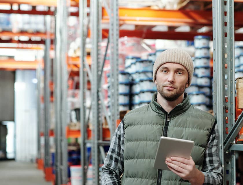 An Assistant Production Manager holding a tablet in a production warehouse ensuring production is within schedule.