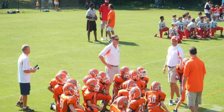 Athletic Director supervising a football game between young teams.