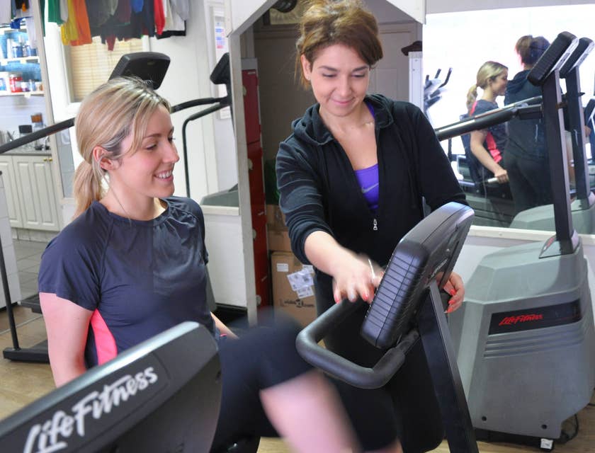 Athletic Trainer next to a woman in a cycling machine.