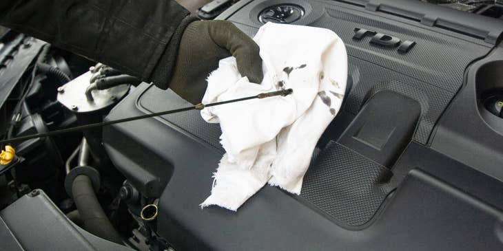Auto Mechanic checking the level of oil in a vehicle.