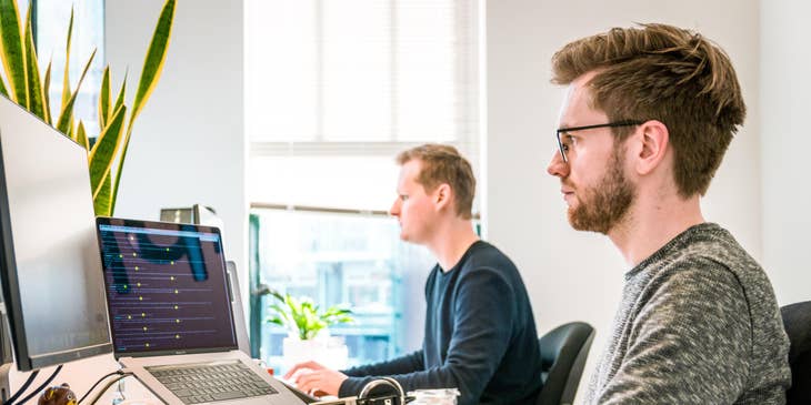 Back End Developers sitting right next to each other and working on their respective computers