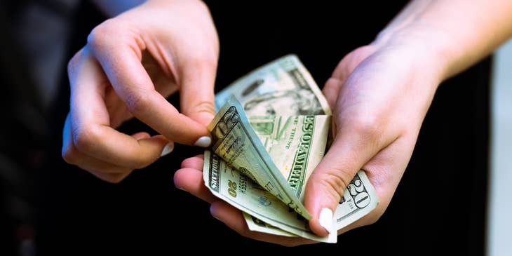 Bank Teller counting twenty dollar bills.