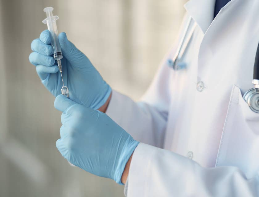 Un profesional de la salud preparando una jeringa, en una empresa de salud.
