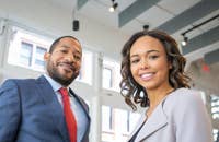 Dos empleados con buena ética laboral sonriendo en una oficina.