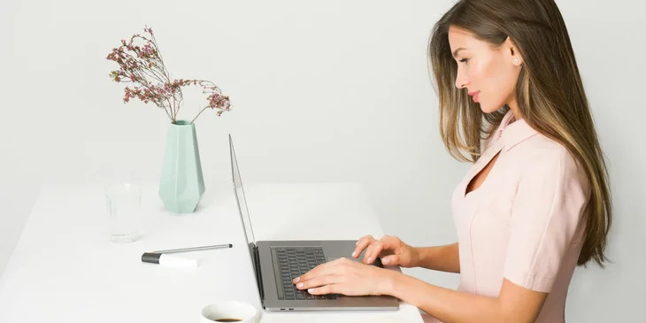 A woman in a pink dress using a laptop.