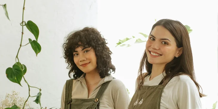 The positive florists in aprons looking at camera.