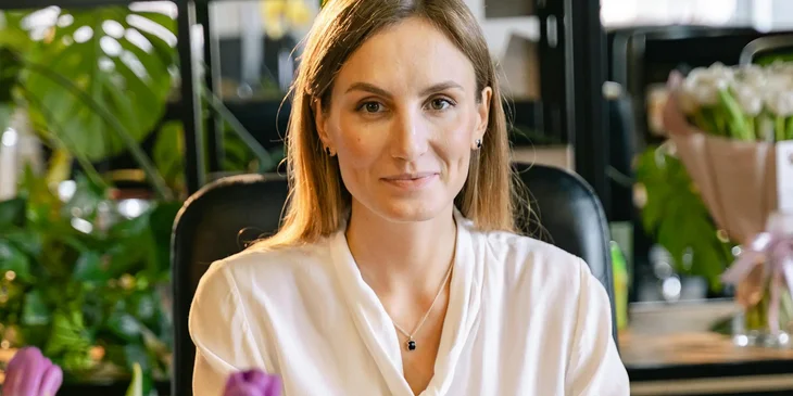 A woman wearing a white blouse smiling at the camera.