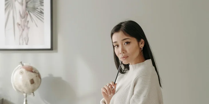 A woman holding a pencil while looking at the camera.