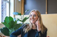 Ofiste gülümseyerek telefonla konuşan bir kadın.
