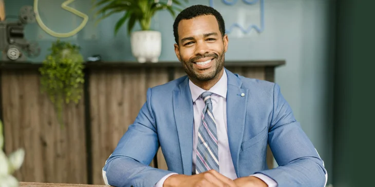 A man in a blue suit sitting by the table.