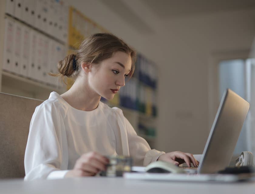 An accounting administrator reading a financial document at a desk.