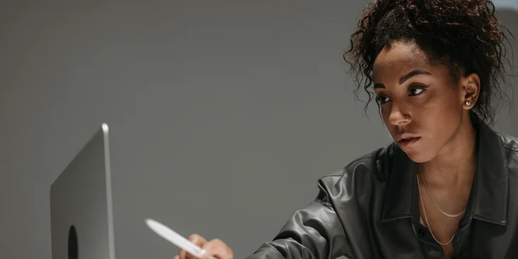 An administrative analyst points to a computer screen using her pen.