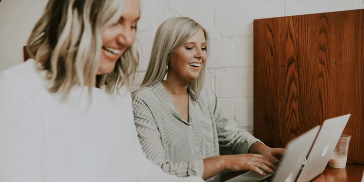 Two women busy on their laptops.