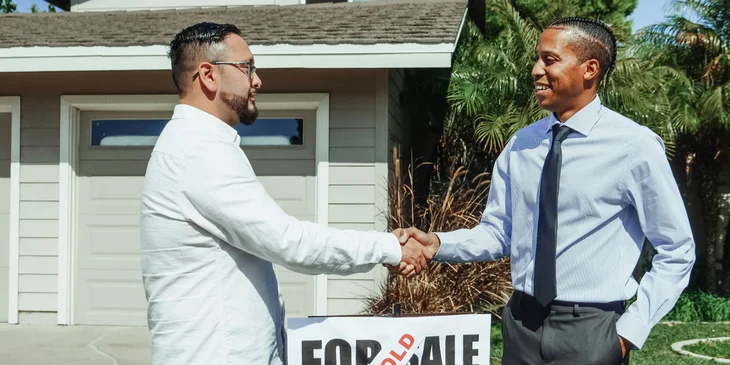 A real estate agent shaking hands with the new owner of the house.