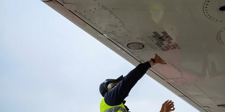 An aircraft maintenance engineer checking the plane's fuel pit.