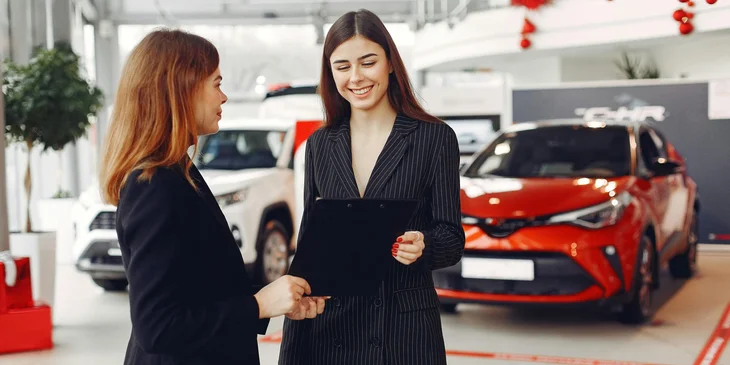 A female car dealer holding a contract.