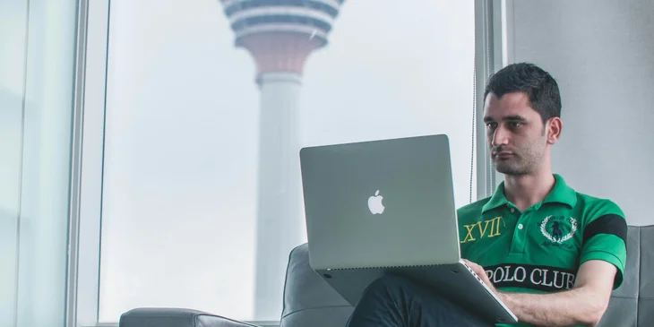A man sitting on a sofa using his laptop.