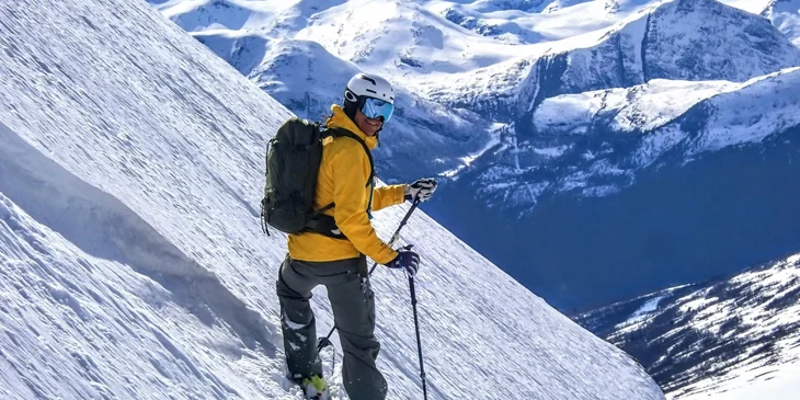 A man with skis standing on a slope.