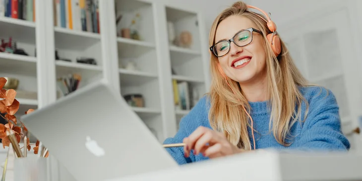 A woman smiling while using a laptop.