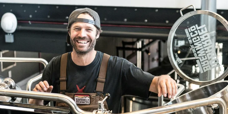 A man smiling as he inspects a machine.