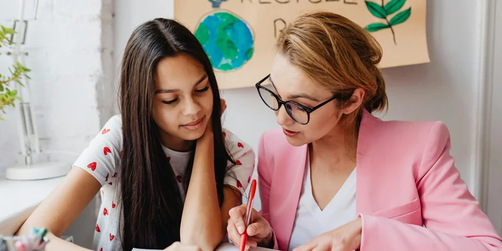 An assessor checking her student's answer on a notebook.